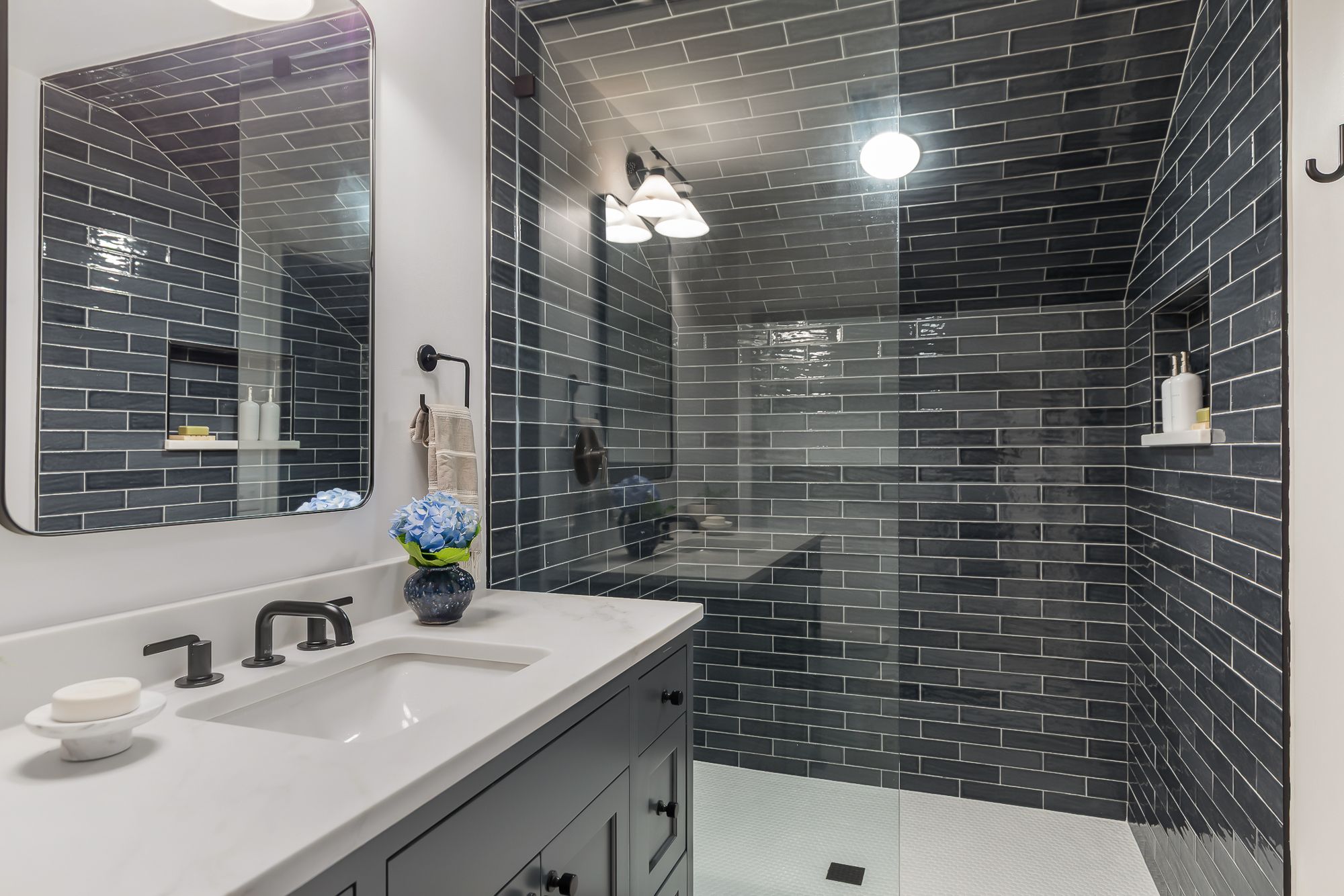 Renovated bath with dark handmade tile shower and marble vanity